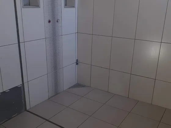 Velký sprchový kout po dokončení hlavních obkladů a dlažby.