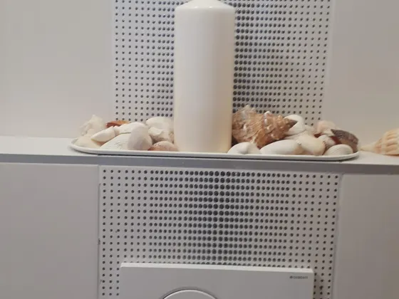 Detail předsazené stěny WC s dekoračním pásem a odkládací plochou.