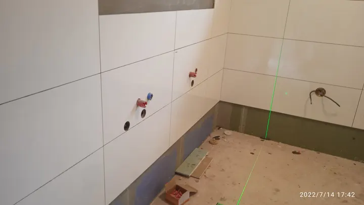 Průběh dokončování koupelny - pokládka velkoformátových obkladů a příprava instalací.