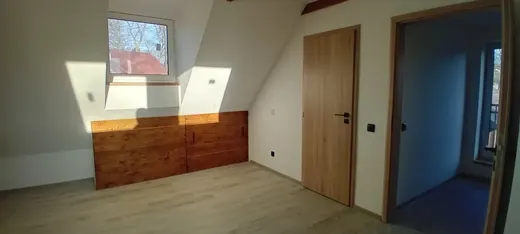 Detail dřevěného obkladu pod oknem a navazující podlahy.