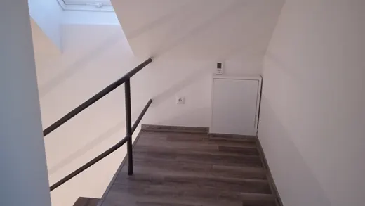 Dolní část schodiště se zábradlím a dokončenými stěnami.