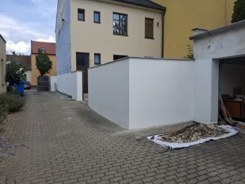 Bílé stěny ve dvoře po sjednocujícím fasádním nátěru.