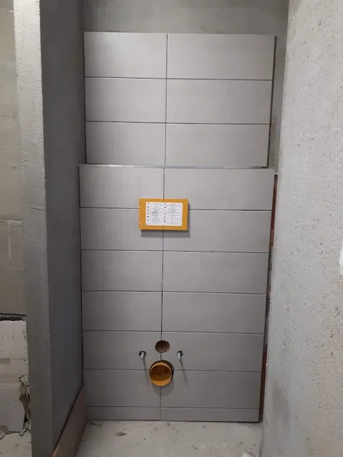 Postupné obkládání stěny za závěsným WC.