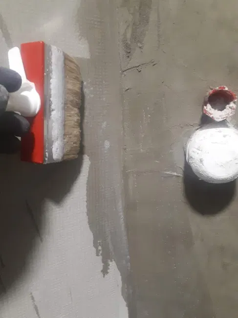 Detail nanášení stěrky v prostoru sprchového koutu.
