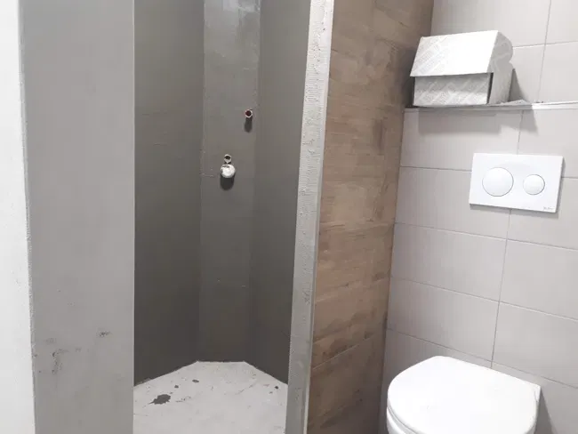 Širší pohled na sprchový prostor a závěsné WC v průběhu prací.